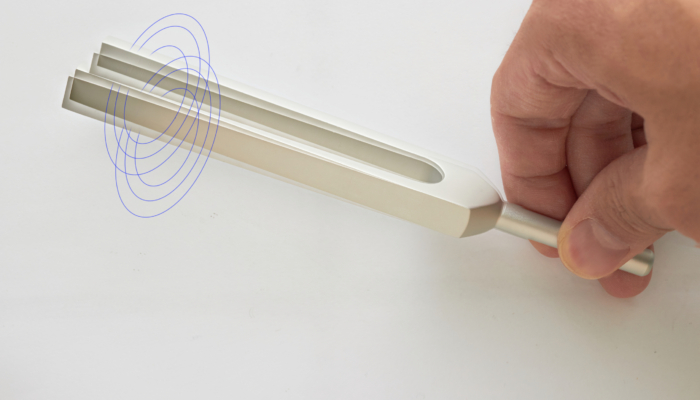 shutterstock_1414794380 A tuning fork vibrating in someone's hand